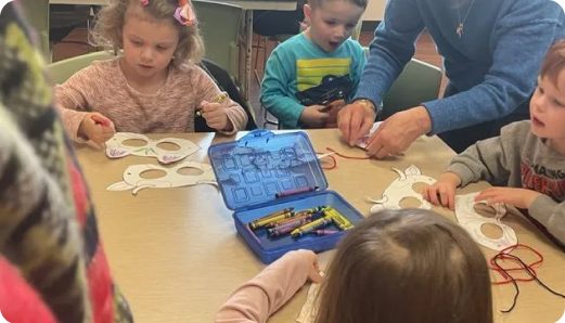 A group of children work on craft projects during a Melody the Monkey workshop.