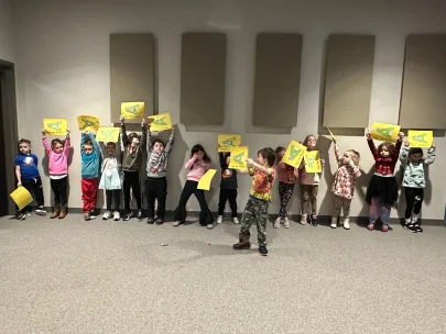 A group of children celebrate the letter A with paper signs.