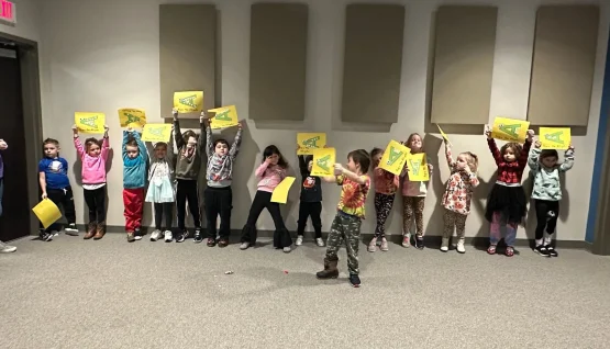 A group of children celebrate the letter A with paper signs.